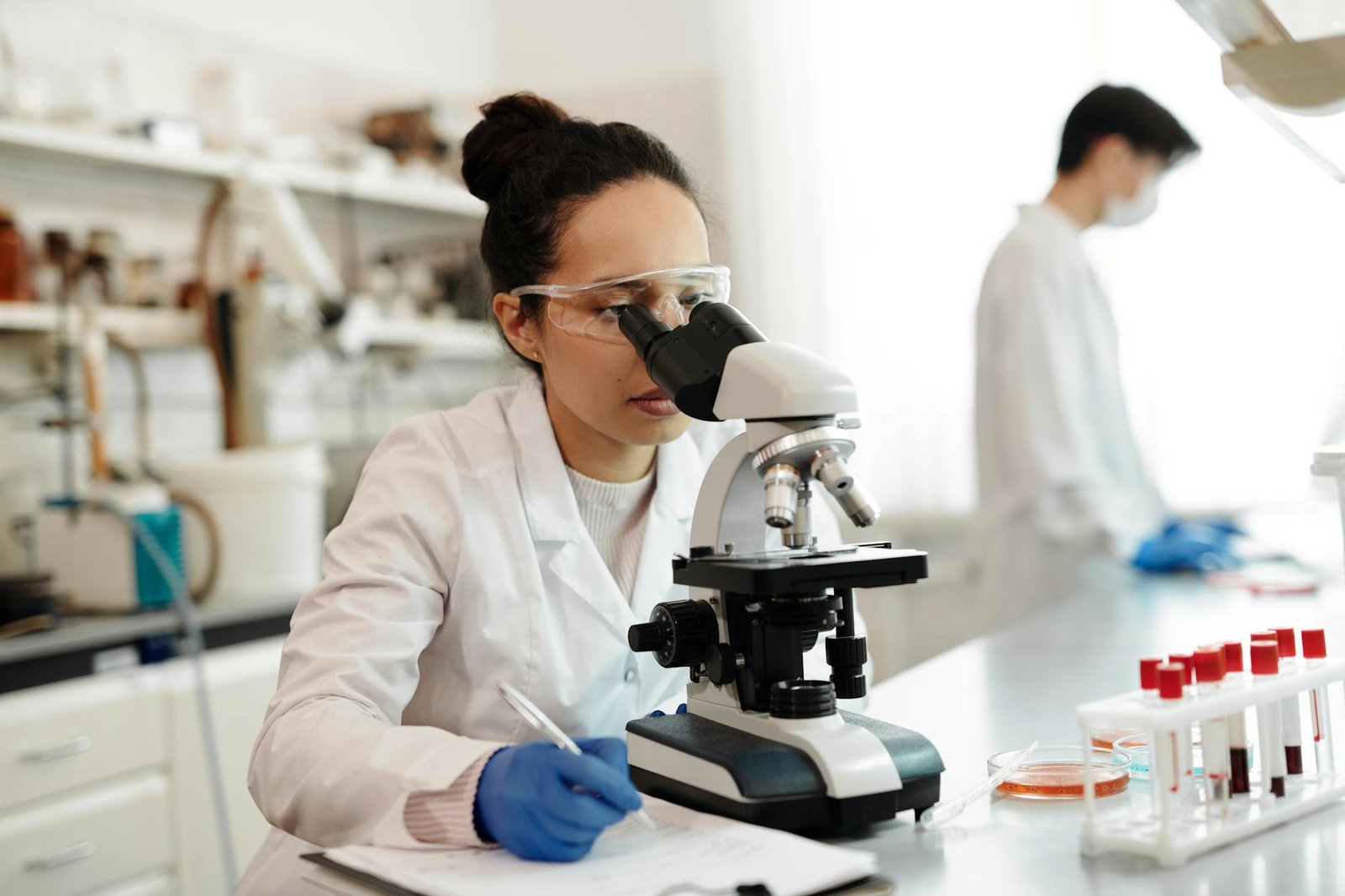 female scientist in white lab coat using a microscope