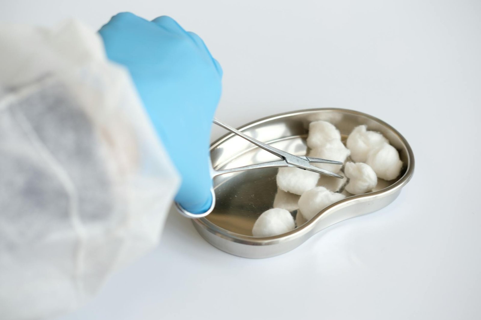 a close up shot of a medical professional using forceps to get a cotton ball