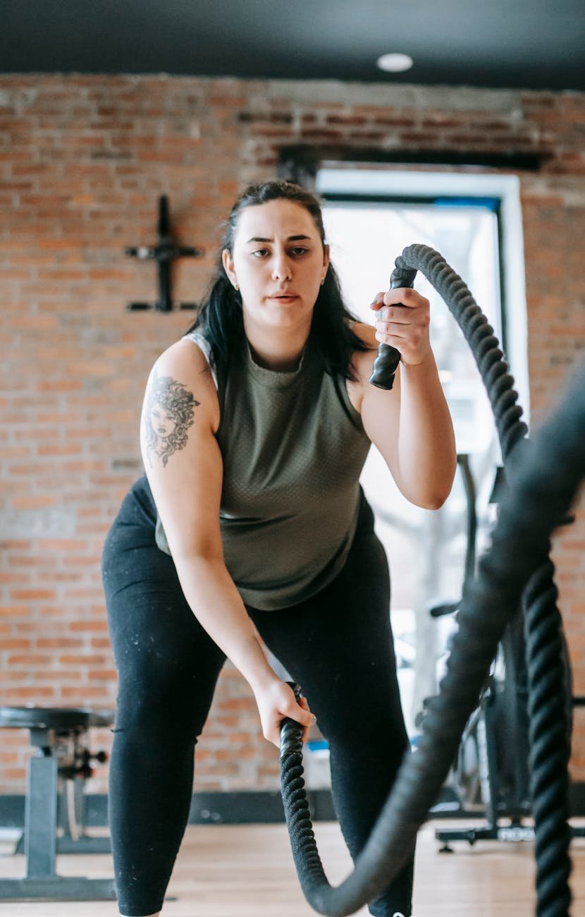 a woman exercising with battle ropes in gym