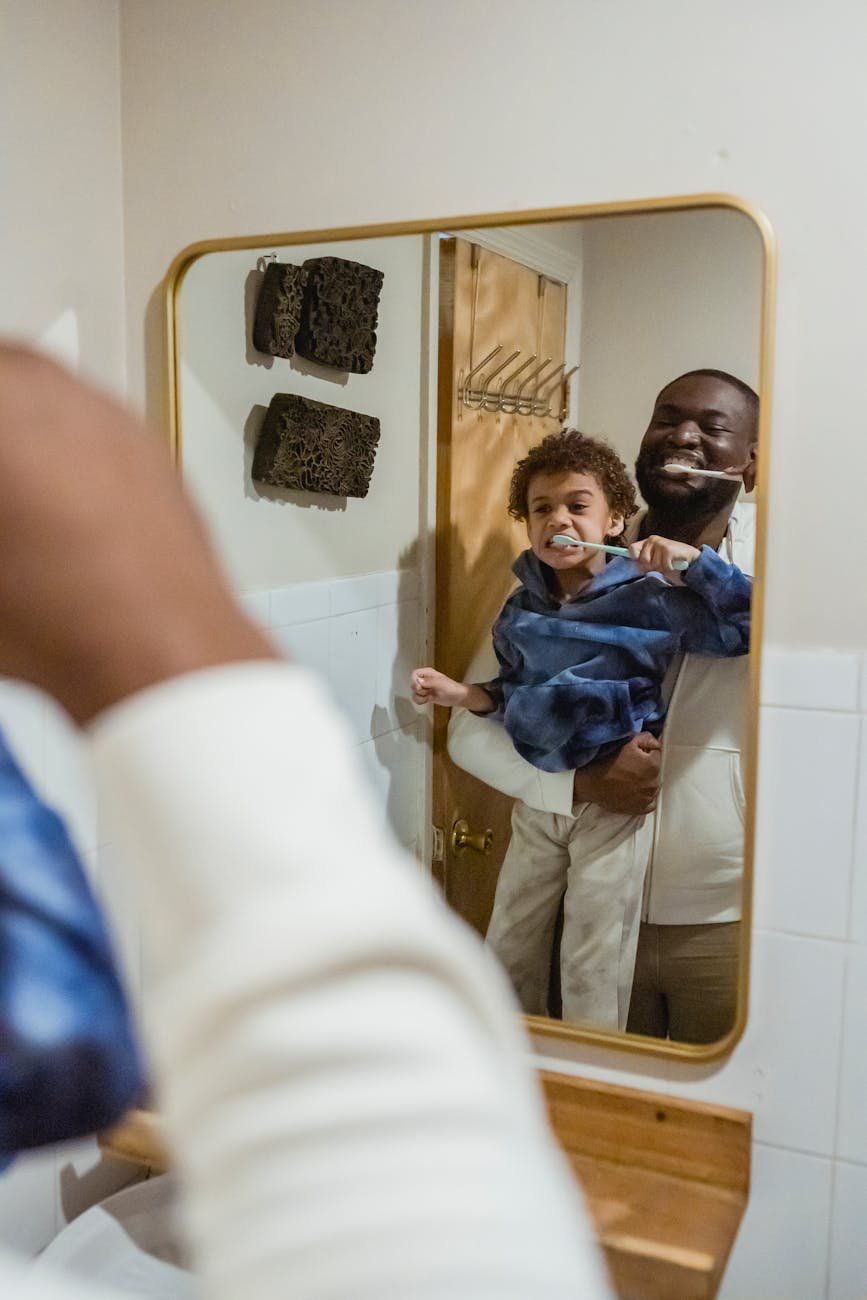 black father and son brushing teeth in bathroom