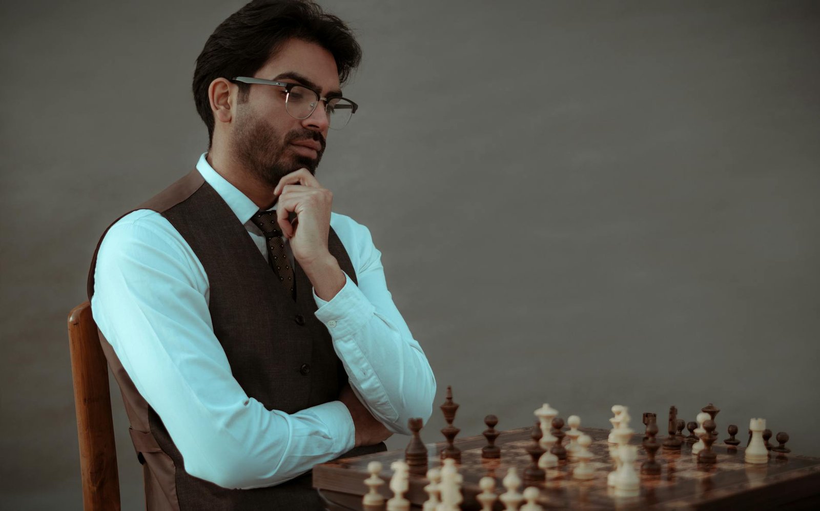 serious ethnic man thinking over tactic of playing chess