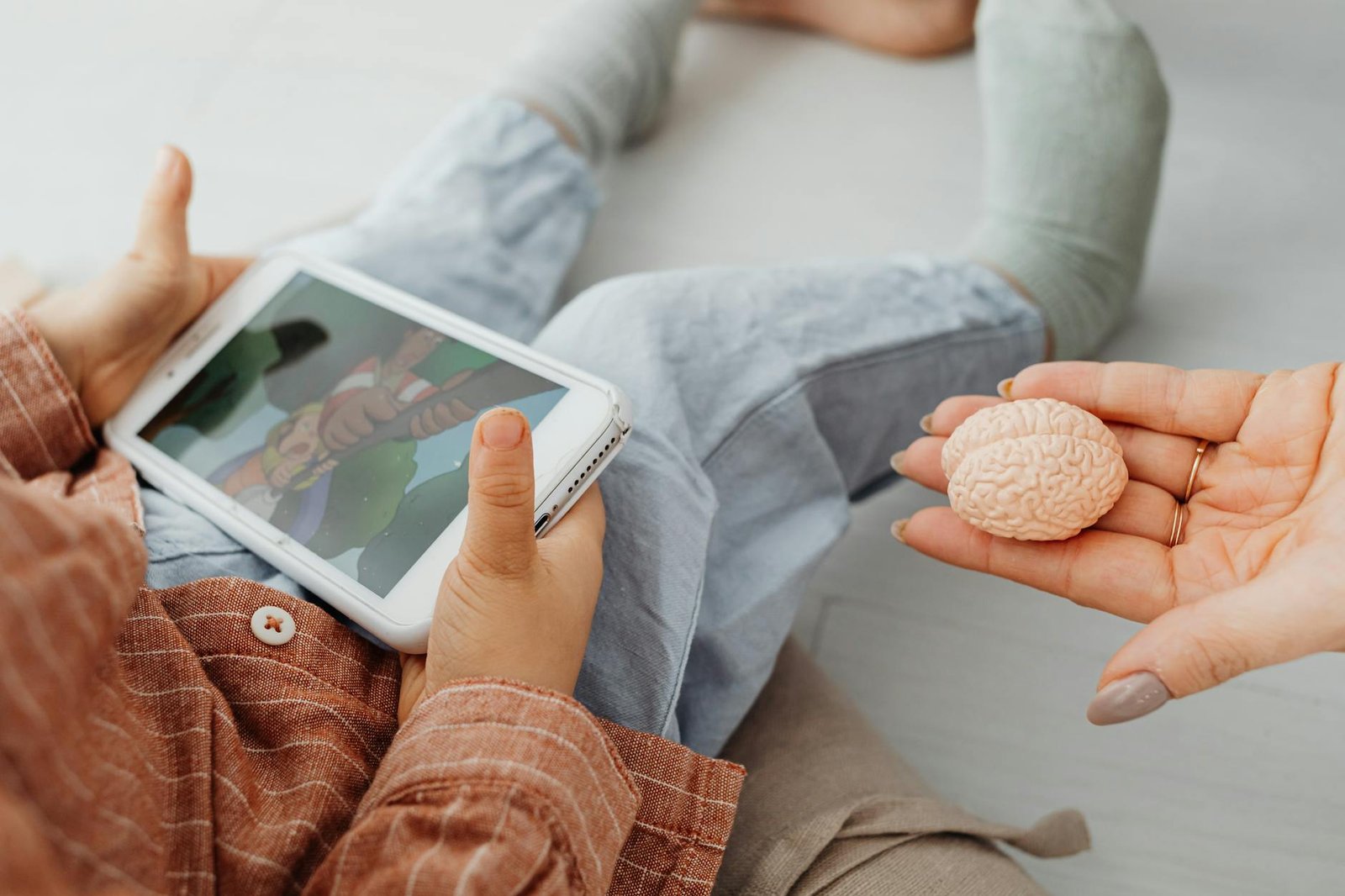 a kid holding a cell phone near a person s hand