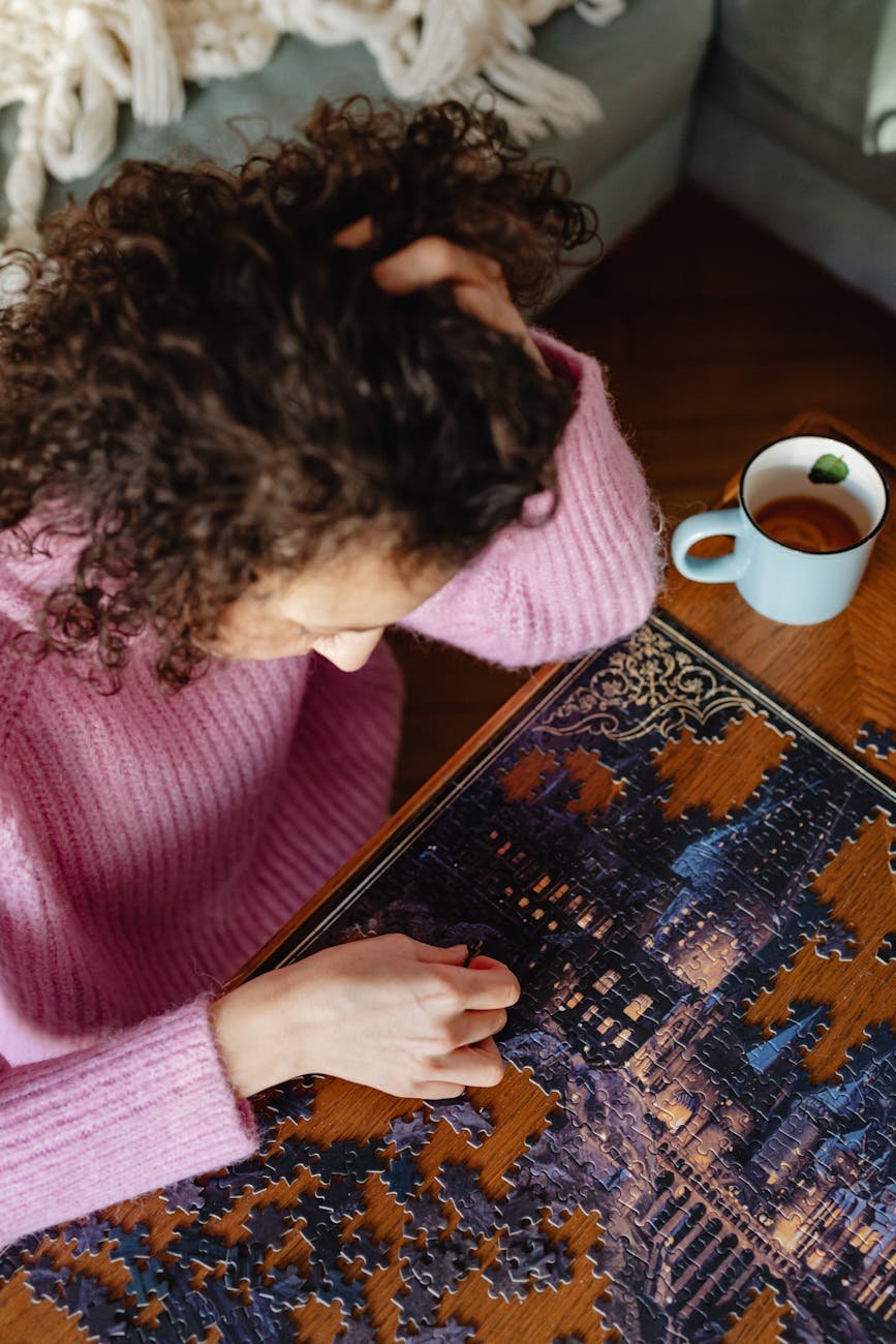 high angle view of a woman in a pink polo neck sweater solving puzzles