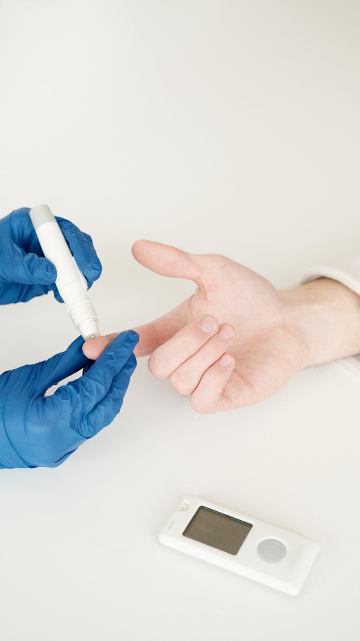 person in blue gloves using a lancet pen on a diabetic person